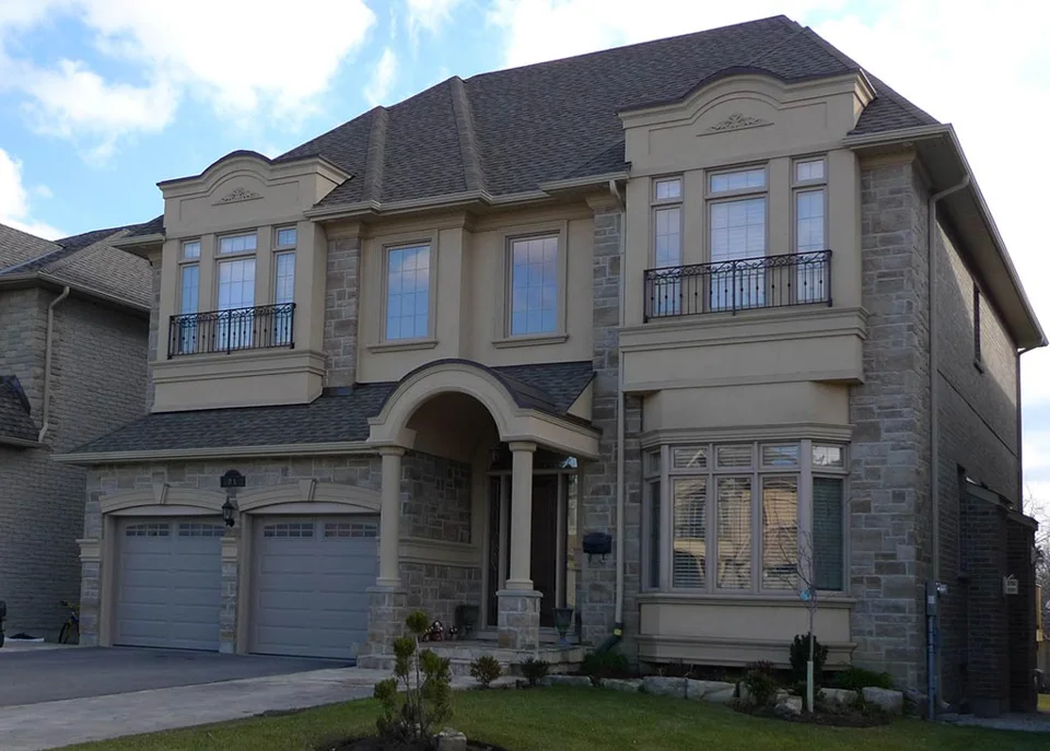 Two-storey house combining stonework and mouldings around the windows.