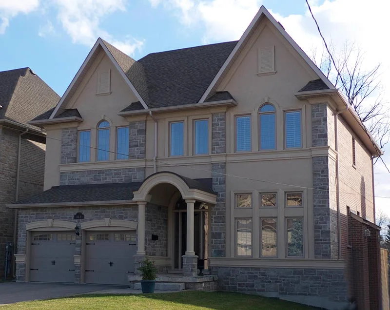 Brick and stucco house with arched entrance and contrasting window trim.