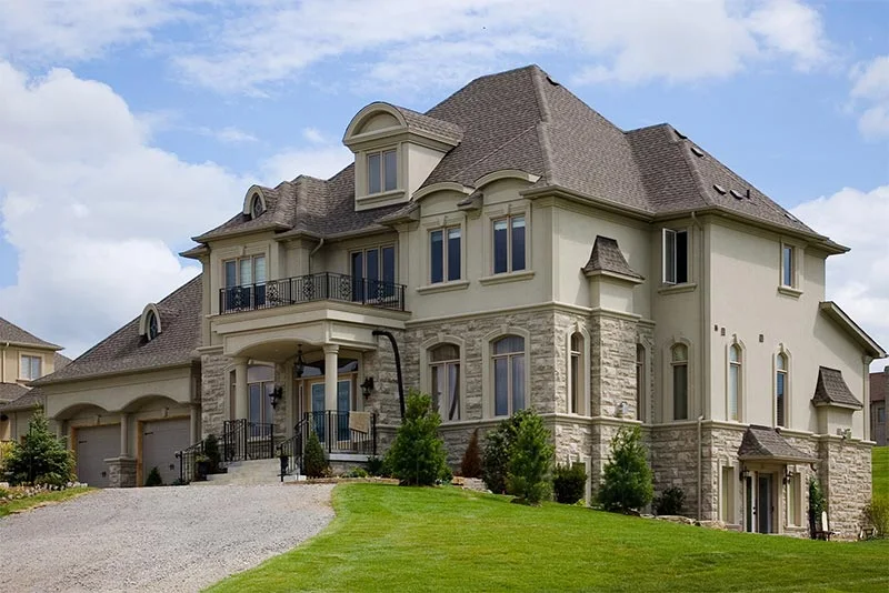 Large house with pale exterior trim and stonework around lower windows.