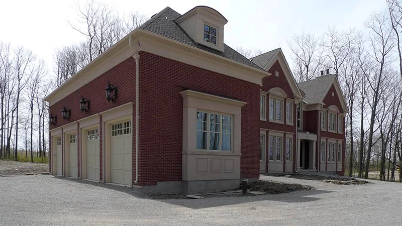 Red brick house with pale corner trim and mouldings around garage doors.
